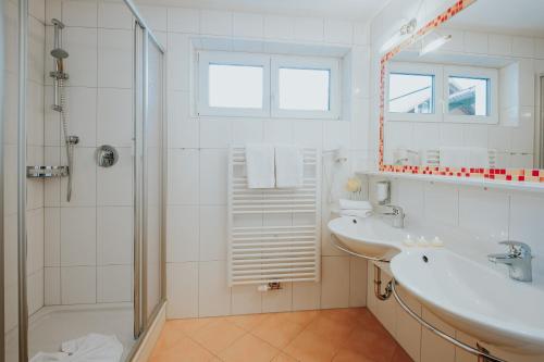 a white bathroom with a sink and a shower at Hotel Schneider Dependance in Obertauern