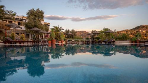 a pool of water with chairs and trees in the background at 4reasons hotel + bistro | 12+ in Yalıkavak