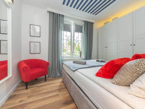um quarto com uma cama grande e uma cadeira vermelha em Glow Apartments, Apartament Długa 69 em Gdansk