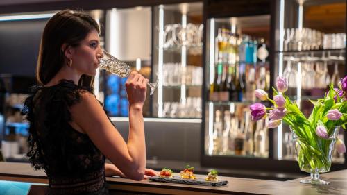 a woman drinking from a wine glass at a bar at Sunstar Hotel & SPA Grindelwald in Grindelwald