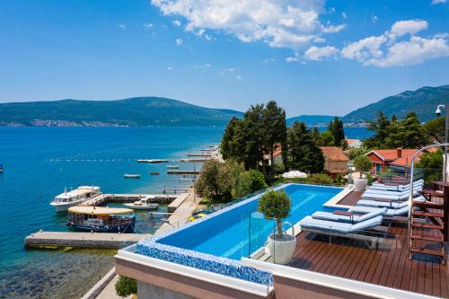a swimming pool next to a body of water with boats at Elysium Tivat in Tivat