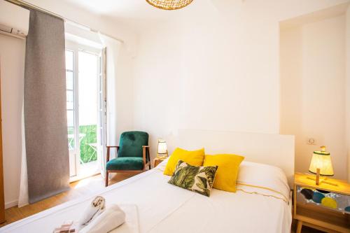 - une chambre avec un lit doté d'oreillers jaunes et d'une chaise verte dans l'établissement PARADISIO 2 AP4237 By Riviera Holiday Homes, à Nice
