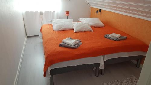 a bedroom with a large orange bed with towels on it at B&B Parksäter in Håcksvik