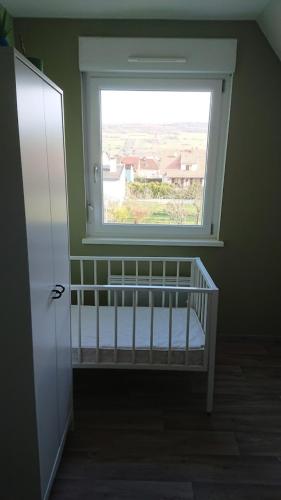 a baby crib in a room with a window at Gîte Alsace maison indépendante proche Strasbourg in Mutzig