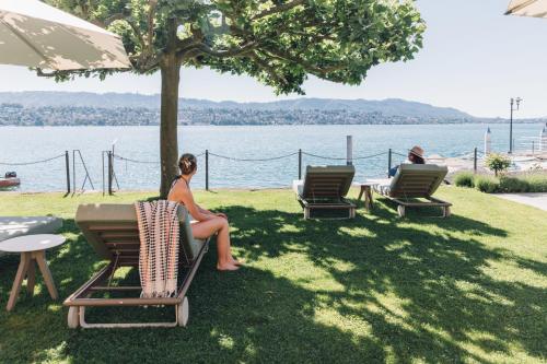a woman sitting on a bench under an umbrella at Seehotel Sonne in Küsnacht