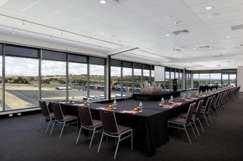 a long table with chairs in a room with windows at Rydges Mount Panorama Bathurst in Bathurst