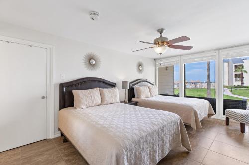 um quarto com 2 camas e uma ventoinha de tecto em Ground floor, spacious patio and only steps away from beach and pool! em South Padre Island