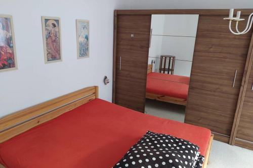 1 dormitorio con cama roja y espejo en Apartmán na Náměstí ve Štramberku en Štramberk
