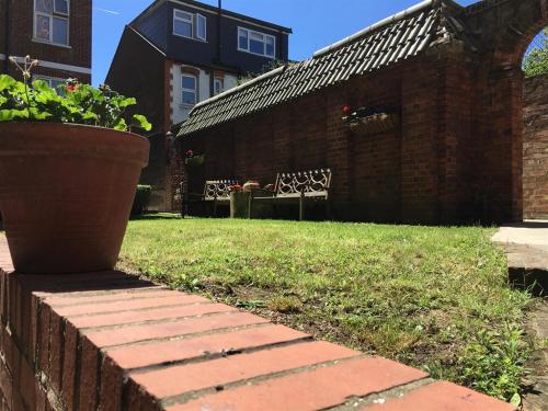 a yard with a brick wall and a potted plant at Marble Apartments Effra Court in London