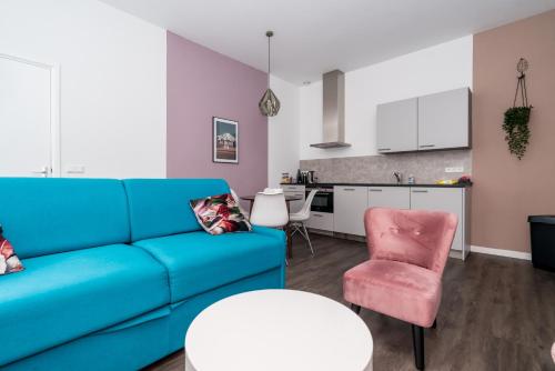 sala de estar con sofá azul y silla rosa en Slapen bij Van-V, en Zierikzee