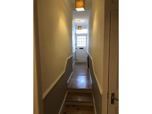un couloir avec un escalier menant à une porte dans l'établissement Marble Apartments Tooting Broadway, à Londres