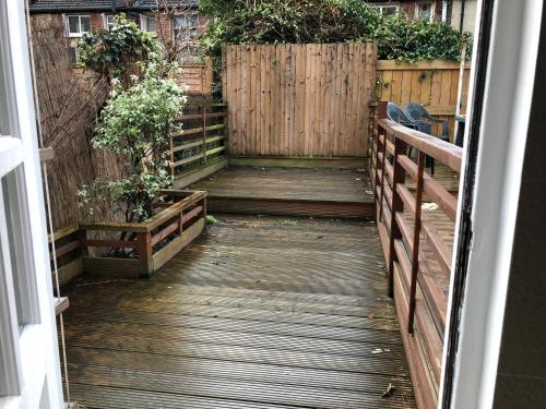 a wooden walkway with potted plants and a fence at Marble Apartments Tooting Broadway in London