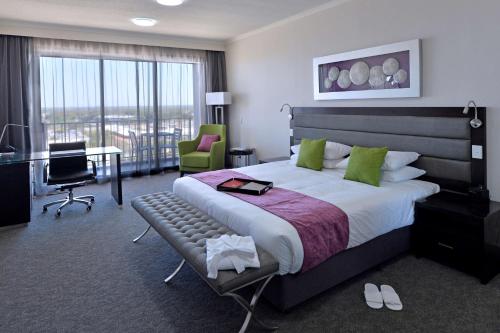 a hotel room with a large bed and a desk and chair at Rydges Palmerston - Darwin in Darwin