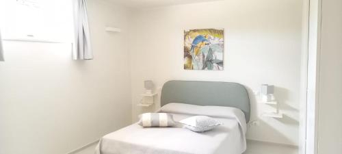 a white room with a bed and a painting at Villa Peter in Ostuni