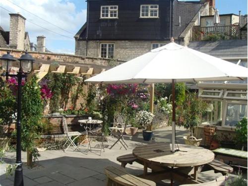 a picnic table with a white umbrella and chairs at The Old Brewhouse in Cirencester