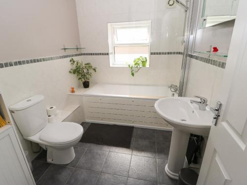 a white bathroom with a toilet and a sink at The Loft at the Lake in Littleborough