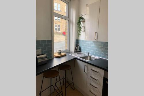 a kitchen with a sink and two bar stools at Stylish studio gem in the heart of Hebden in Hebden Bridge