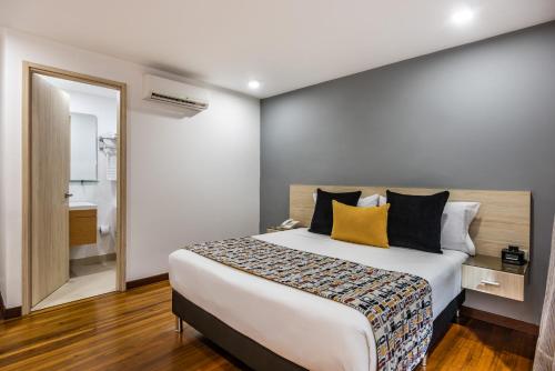 a bedroom with a large bed and a mirror at Hotel Asturias Medellin in Medellín