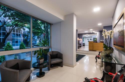 
a living room filled with furniture and a large window at Hotel Asturias Medellin in Medellín
