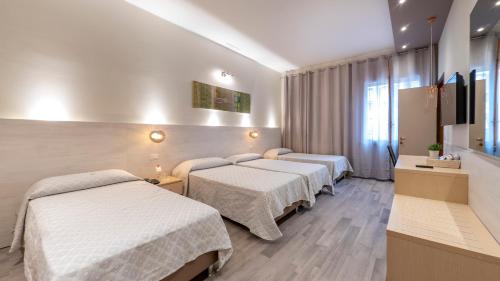 a hotel room with three beds and a television at Hotel San Marco in Reggio Emilia