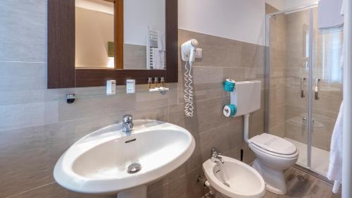 a bathroom with a sink and a toilet and a mirror at Hotel San Marco in Reggio Emilia