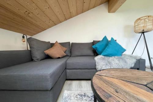 a living room with a gray couch with pillows at Gemütliche Ferienwohnung im DG am Tegernsee - Bergblick, Ruhe & ganz viel Platz in Bad Wiessee