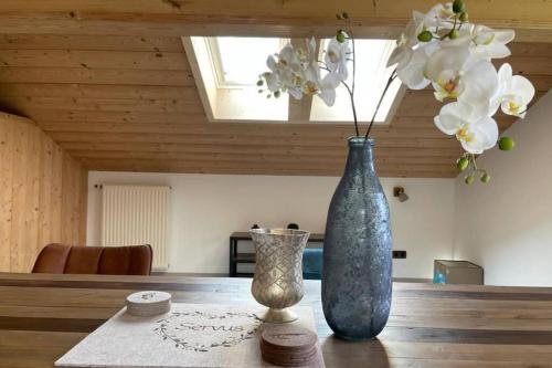 two vases sitting on a wooden table with white flowers at Gemütliche Ferienwohnung im DG am Tegernsee - Bergblick, Ruhe & ganz viel Platz in Bad Wiessee