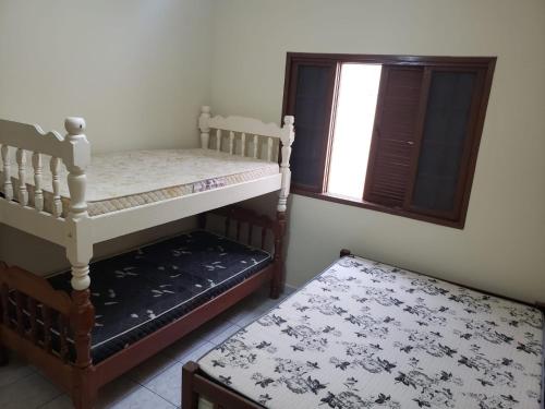 a bedroom with two bunk beds and a window at Casa em Peruíbe in Peruíbe
