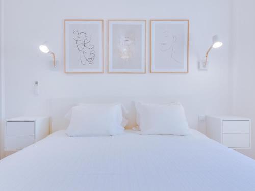 a white bedroom with four pictures on the wall at AL - Apartamento Miratlântico in Quarteira