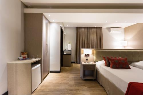 a hotel room with a bed and a desk at Faial Prime Suítes in Florianópolis