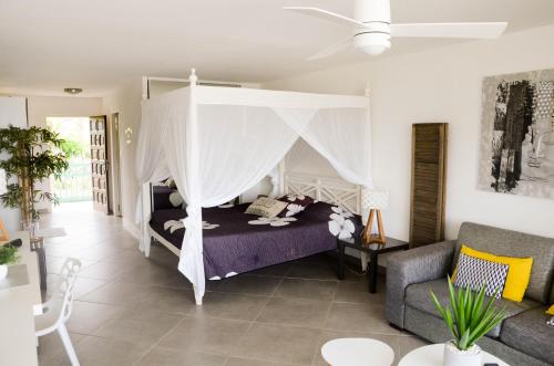 1 dormitorio con cama con dosel y sofá en Un petit coin de paradis - Ocean view Orient Bay - St Barthélémy, en Cul de Sac