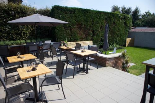 a patio with tables and chairs and an umbrella at Hotel Fi'Lin in Machelen