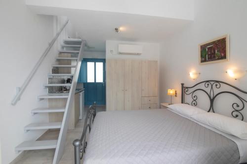 a white bedroom with a bed and a staircase at KAMARADO STUDIOS in Kamarai