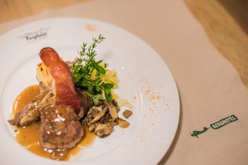 a plate of food with meat and vegetables on a table at Berghotel - Sexten in Sesto