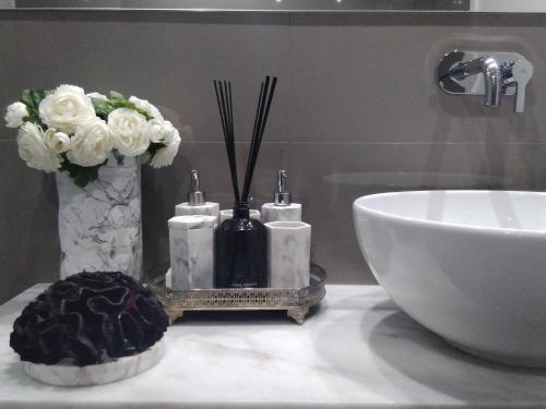 a bathroom counter with a sink and flowers and a vase at Luxury 3 Bedroom Penthouse With Private Garage in Braga