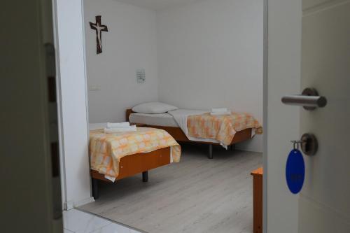 two beds in a room with a cross on the wall at Pansion Milena in Međugorje