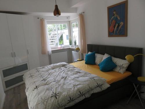 ein Schlafzimmer mit einem Bett mit blauen Kissen und einem Fenster in der Unterkunft Villa Grassenberg in Marburg an der Lahn