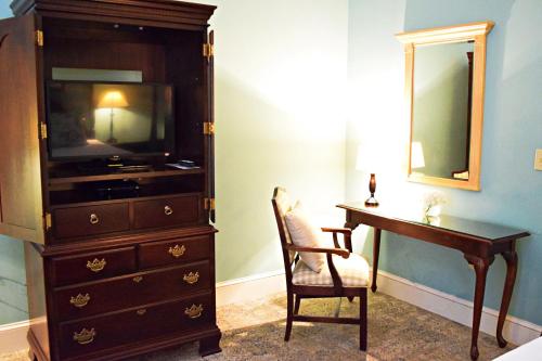 a bedroom with a dresser and a desk and a television at JH Adams Inn, Trademark Collection by Wyndham in High Point