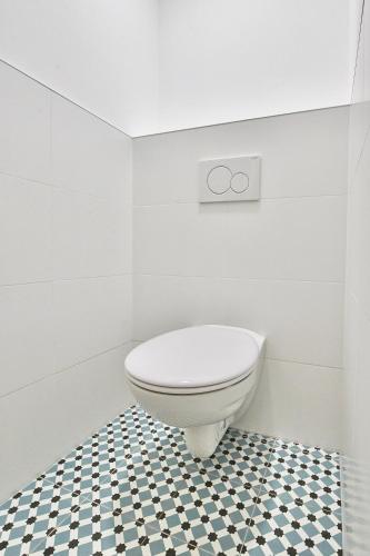 a white toilet in a bathroom with a black and white floor at Altstadt Apartments Melk mit Sauna in Melk