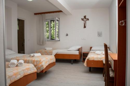 a room with three beds and a cross on the wall at Pansion Milena in Međugorje