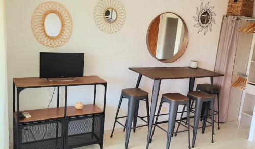 ラ・グランド・モットにあるStudio Piscine à 5 minutes des plages du couchantのテーブル2つとスツール、鏡のある部屋