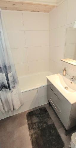 une salle de bain blanche avec un lavabo et une baignoire dans l'établissement Studio Piscine à 5 minutes des plages du couchant, à La Grande Motte