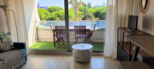 ラ・グランド・モットにあるStudio Piscine à 5 minutes des plages du couchantのリビングルーム(テーブルと椅子付きのバルコニー付)