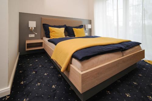 a bedroom with a large bed with blue and yellow pillows at Gästehaus Weinberge in Elsterwerda