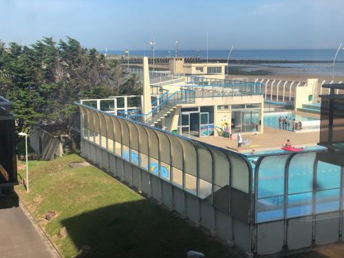 un bâtiment avec une piscine à côté d'une plage dans l'établissement Le 84, à Courseulles-sur-Mer