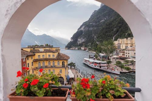 a view of a river from a window with flowers at Hotel Centrale in Riva del Garda