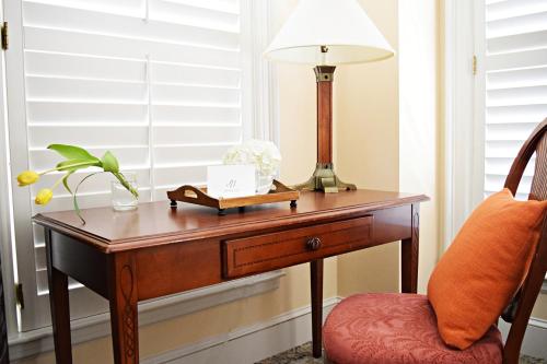 a desk with a lamp on it next to a chair at JH Adams Inn, Trademark Collection by Wyndham in High Point