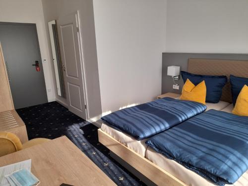 a bedroom with a bed with blue and yellow pillows at Gästehaus Weinberge in Elsterwerda