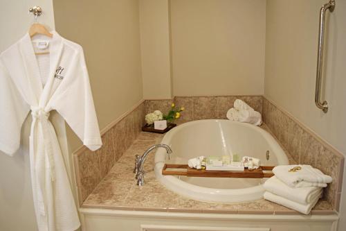 a bathroom with a tub and a sink with towels at JH Adams Inn, Trademark Collection by Wyndham in High Point
