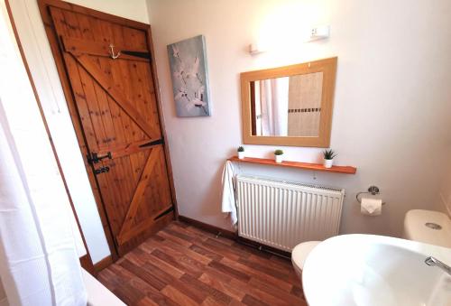 a bathroom with a wooden door and a sink at Grosmont Cottage, Ruswarp in Whitby